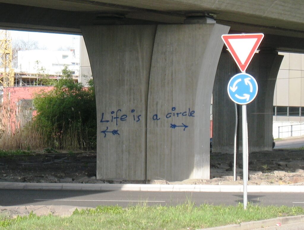 „Das Leben ist ein Kreis(lauf)“ – am Brückenpfeiler in einem Verkehrskreisel in Konstanz 